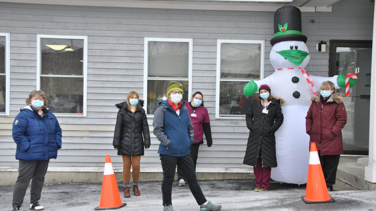 NMC staff posing outside of the covid vaccine center with an inflatable snowman