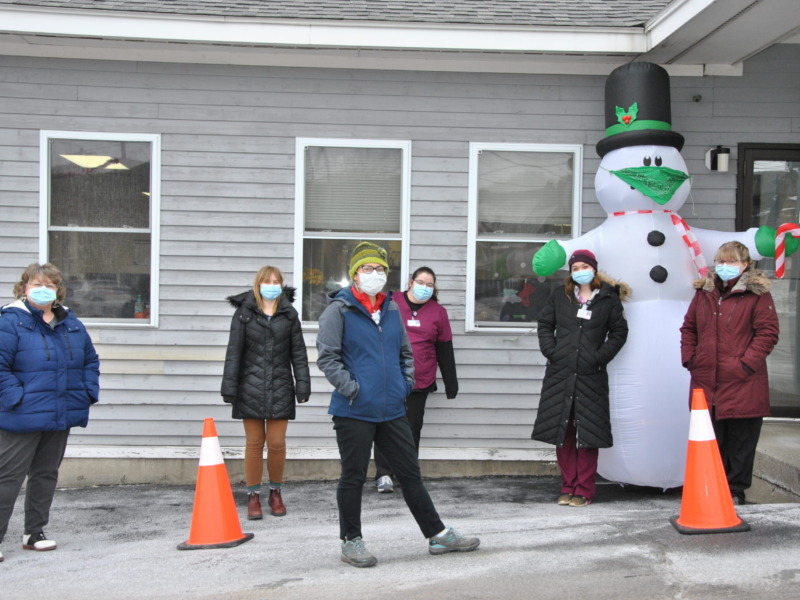 NMC staff posing outside of the covid vaccine center with an inflatable snowman