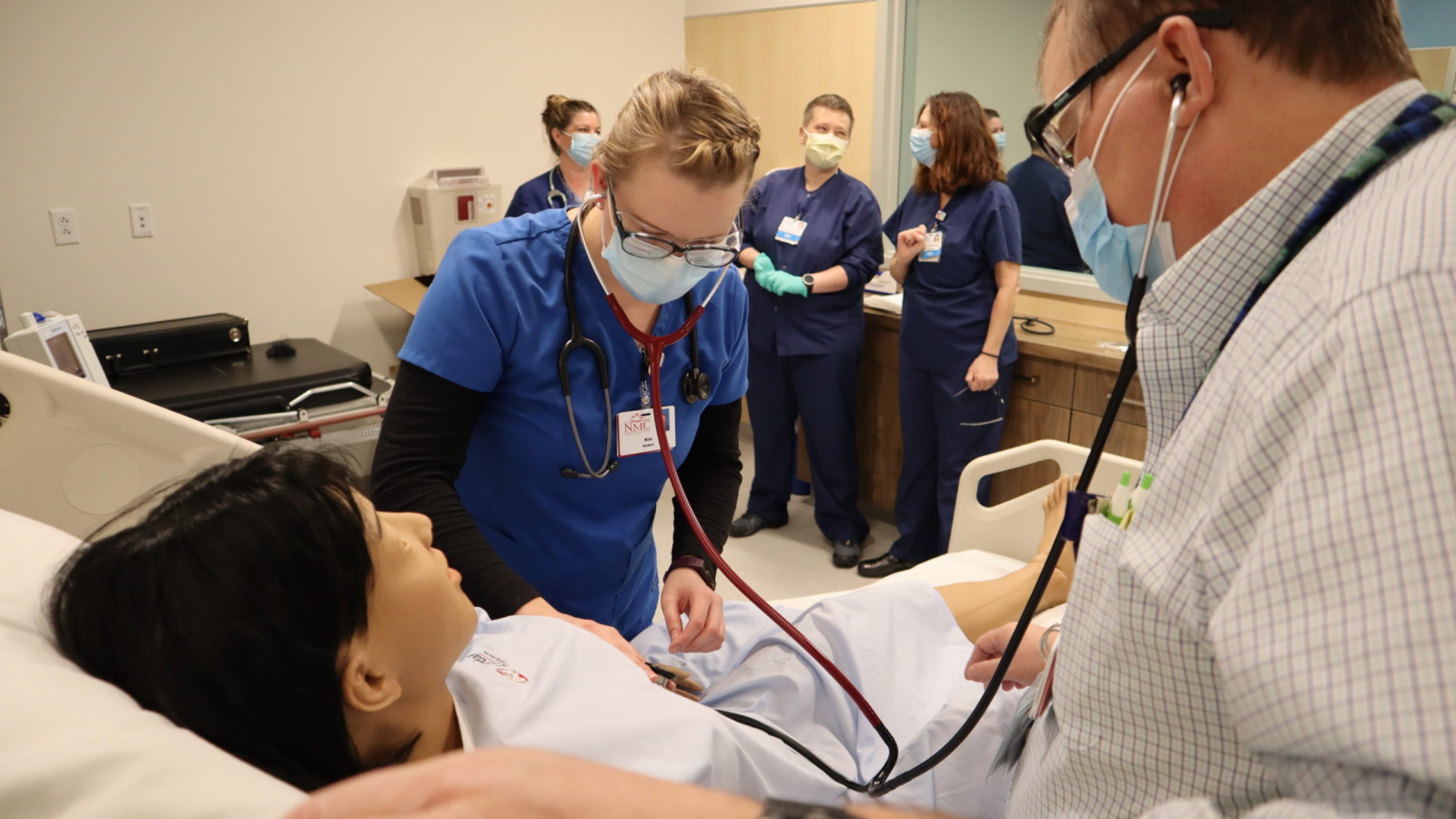 Nurses and instructor caring for a lifelike mannequin patient at NMCs training center