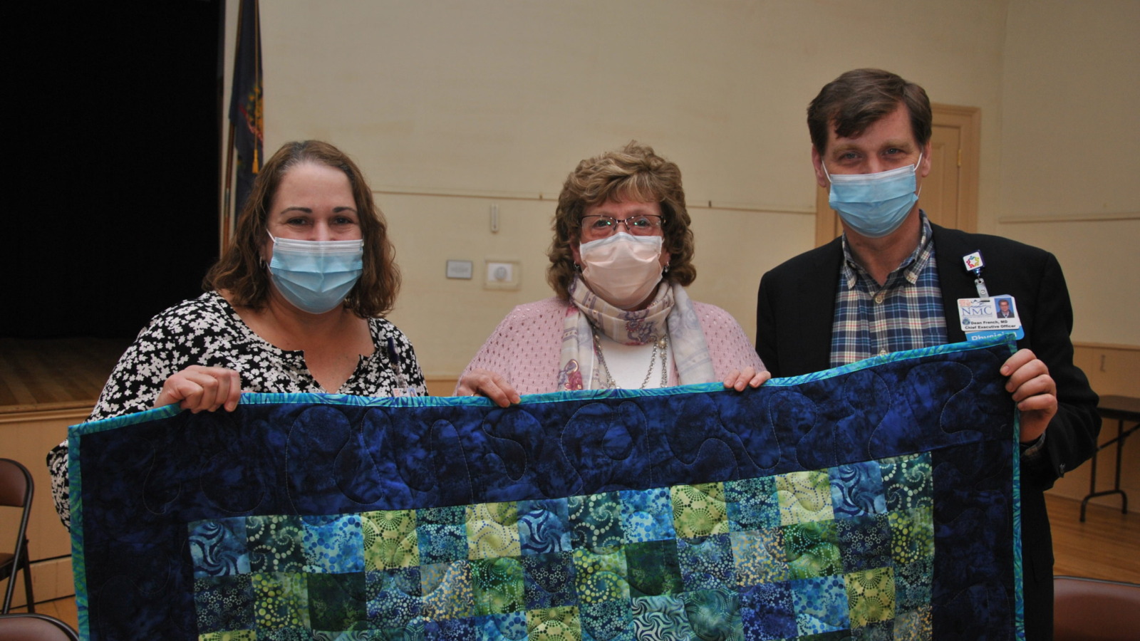 NMC Volunteer Bonnie Evans presenting a quilt to NMC Leadership