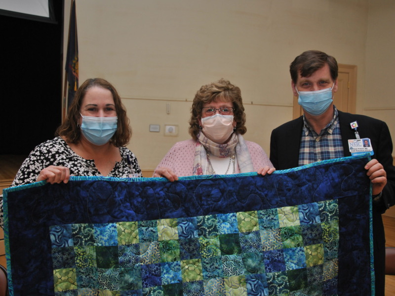 NMC Volunteer Bonnie Evans presenting a quilt to NMC Leadership
