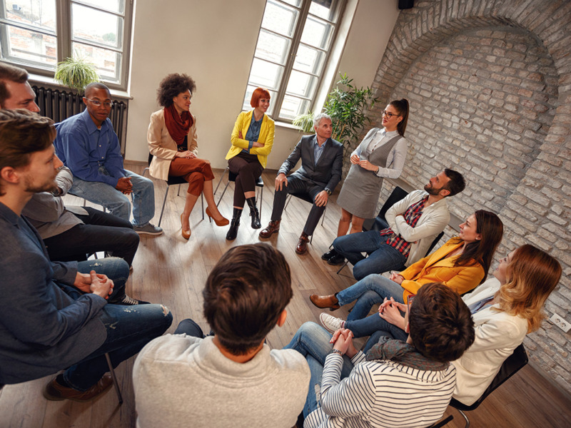 group of people sitting around a circle having a conversation