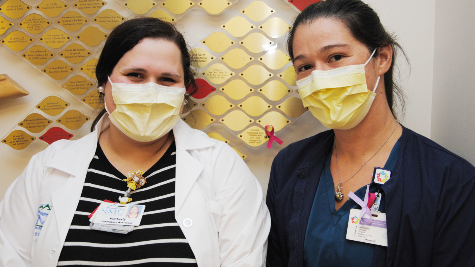 Staff wearing surgical masks standing in front of NMC's Tree of Life