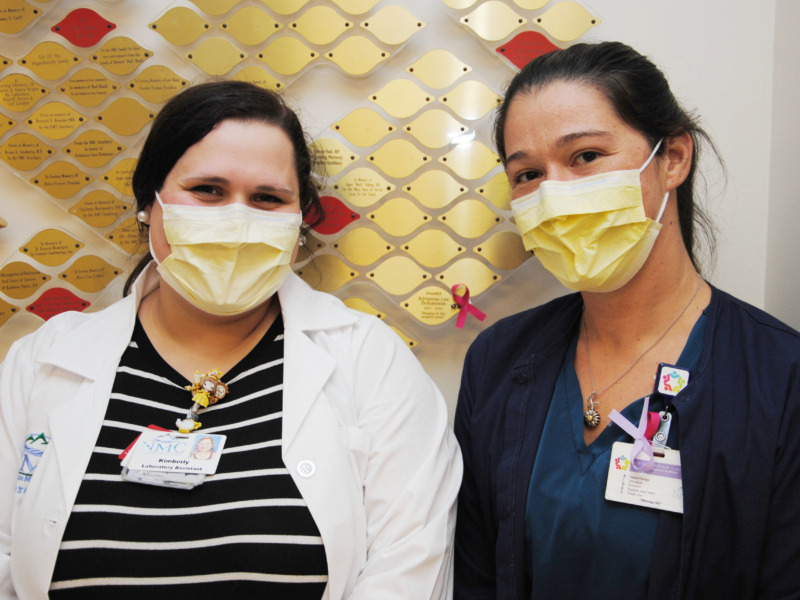 Staff wearing surgical masks standing in front of NMC's Tree of Life