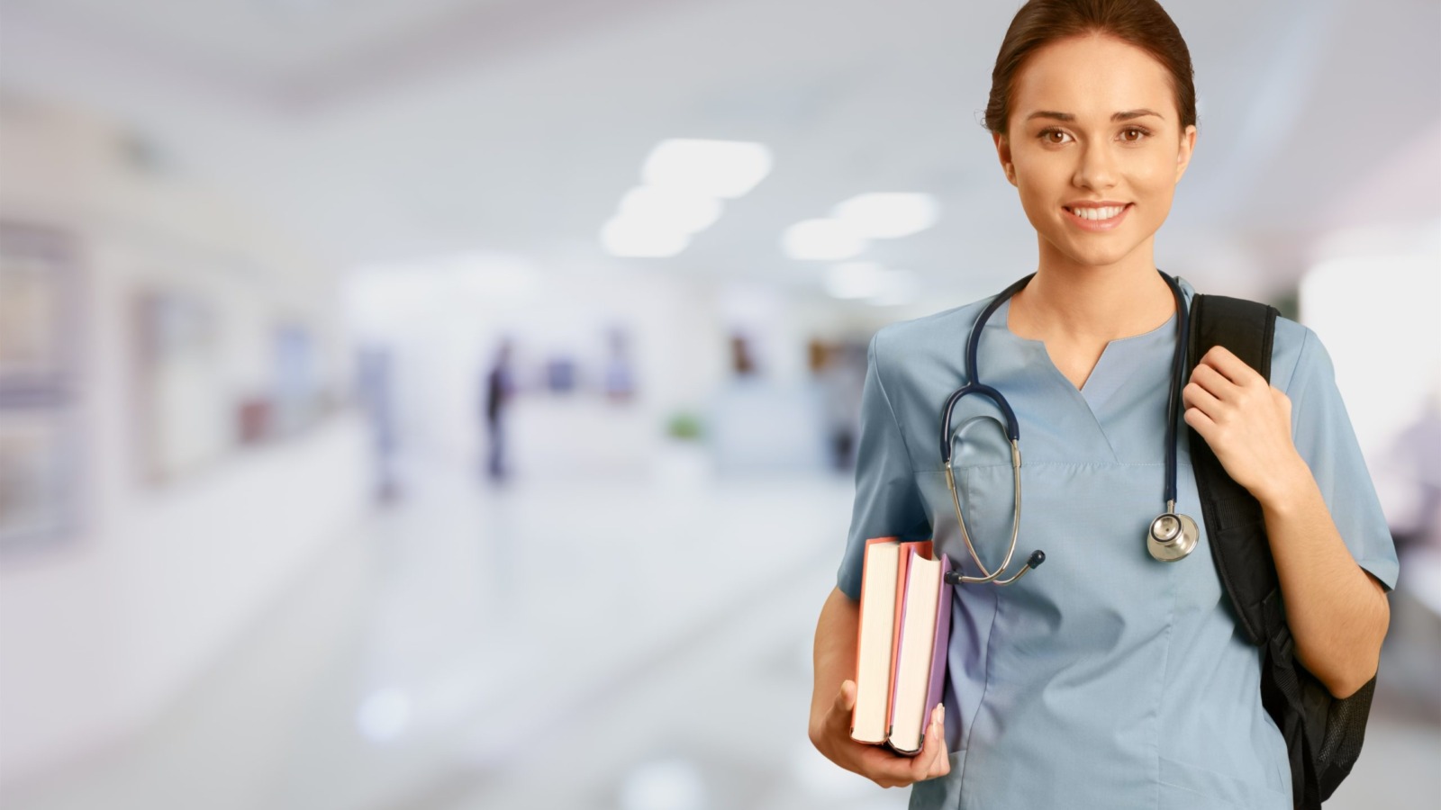 Young Nurse holding books and wearing a stethoscope and backpack over shoulder