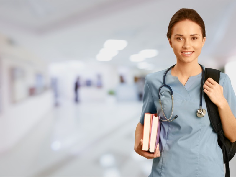 Young Nurse holding books and wearing a stethoscope and backpack over shoulder