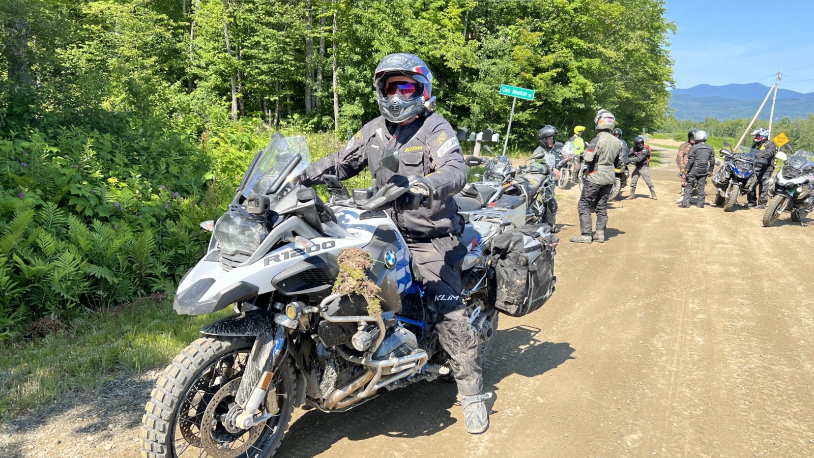group of motorcyclist on a dirt road with Vermont mountains in the background