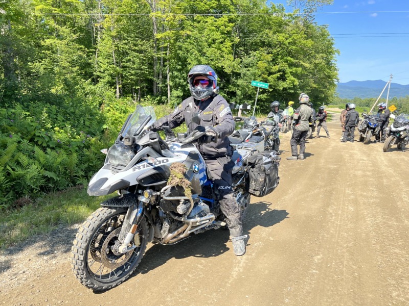 group of motorcyclist on a dirt road with Vermont mountains in the background