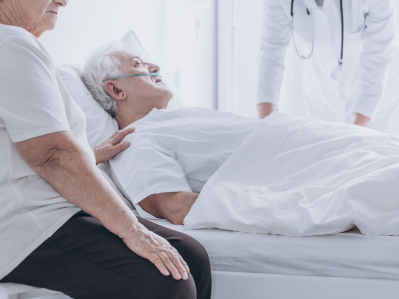 close up image of a patient in a hospital bed, accompanied by a doctor and family member