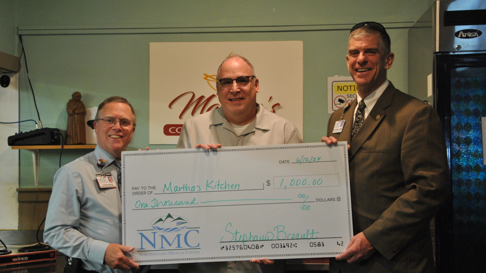 Peter Wright, CEO Northwestern Medical Center and Jonathan Billings, COO present a ceremonial check to a representative of Martha's Kitchen