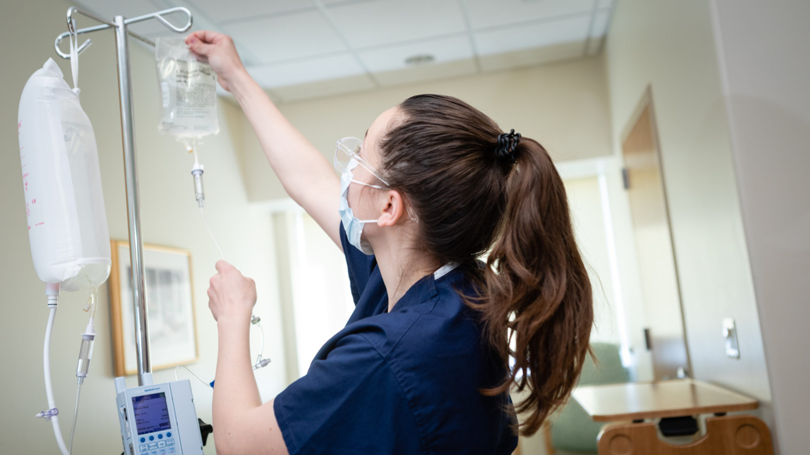 Nurse hanging an IV bag in a patient room
