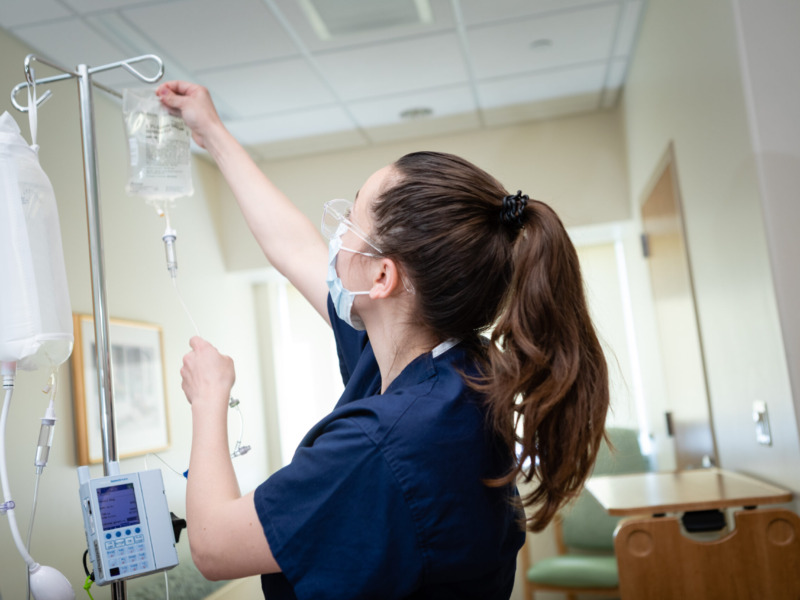 Nurse hanging an IV bag in a patient room