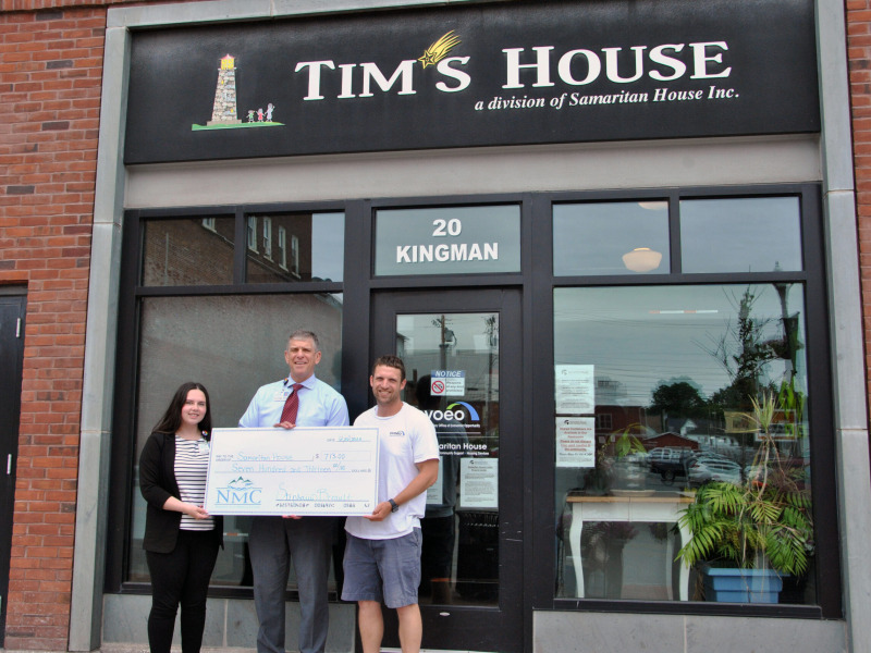 Peter Wright, CEO of Northwestern Medical Center, handing a ceremonial check to representatives of Tim's House, while standing in front of Tim's house at 20 Kingman St. St. Albans vermont