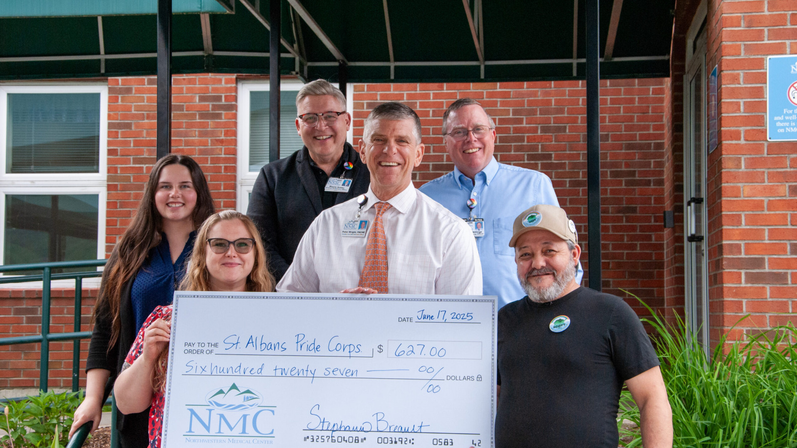 Peter Wright, CEO of Northwestern Medical Center, and other representatives from NMC shown presenting a ceremonial check to the St. Albans Pride Corps..
