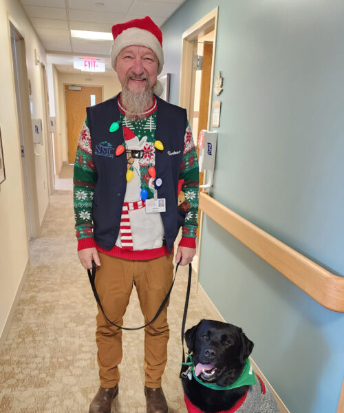 Pet Therapy volunteers Michael and his dog Lemmy posed in holiday sweaters