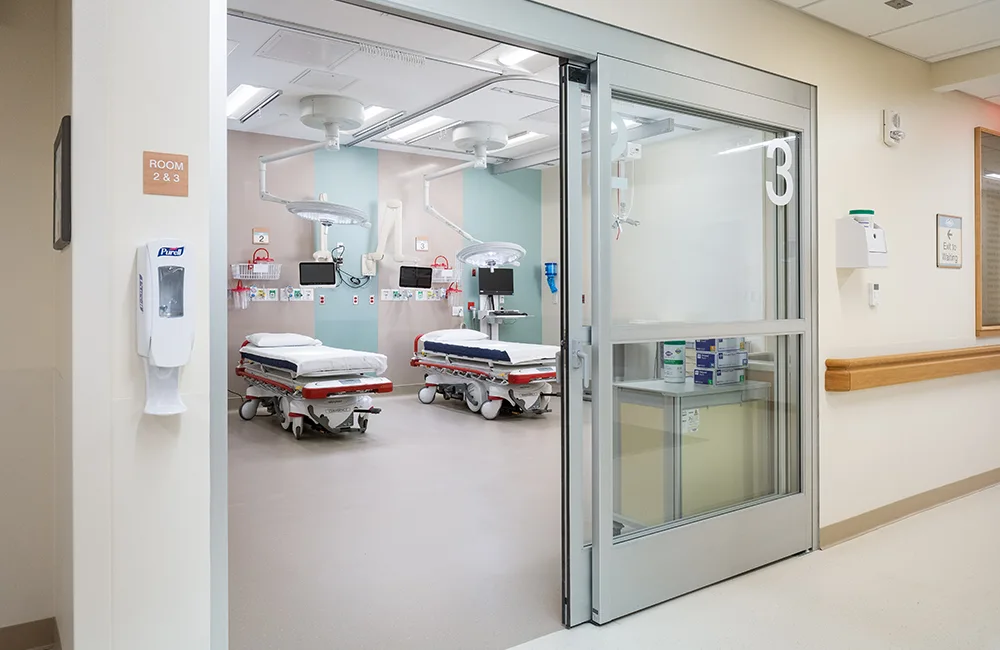 Emergency department room with two beds and large glass sliding door