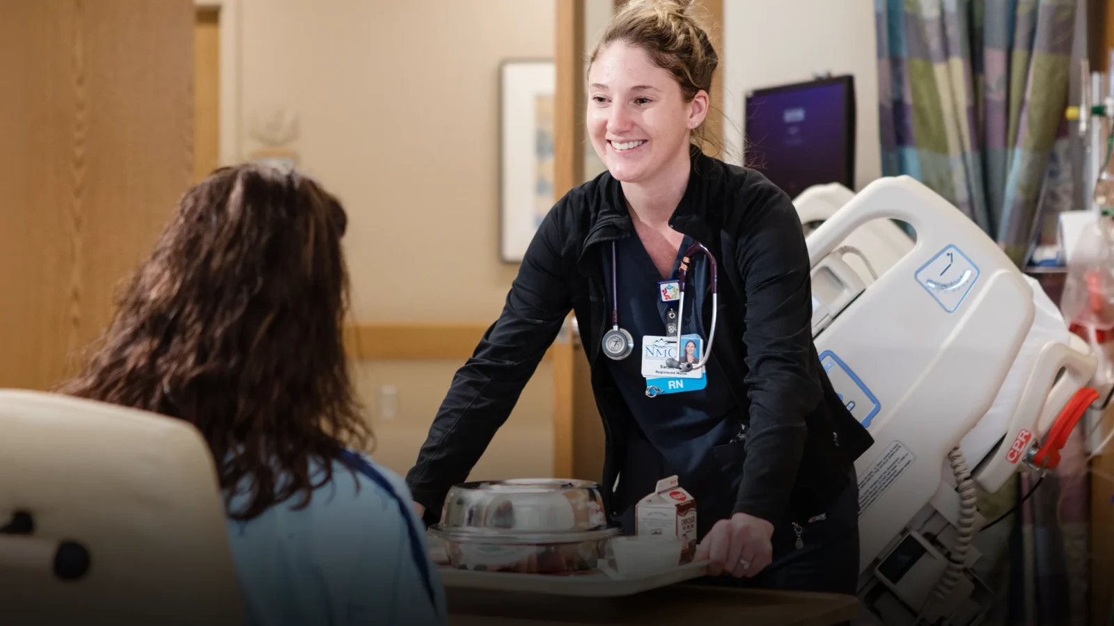 Nurse placing a tray of food in front of a hospital patient
