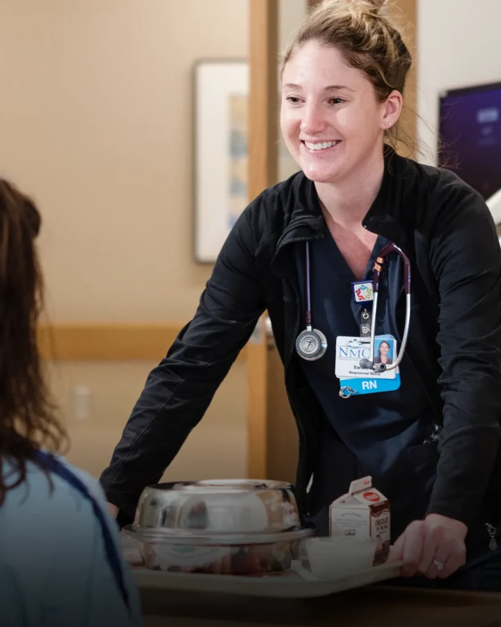 Nurse placing a tray of food in front of a hospital patient