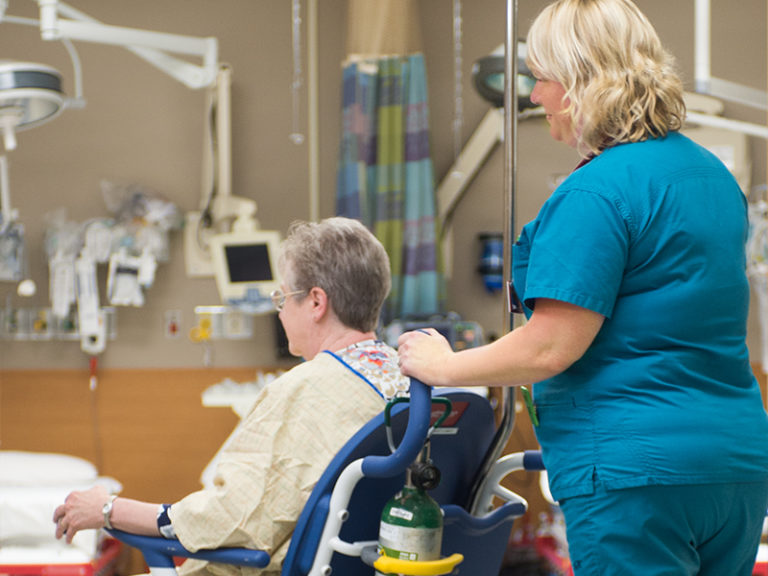 Nurse wheeling patient through emergency department in wheelchair