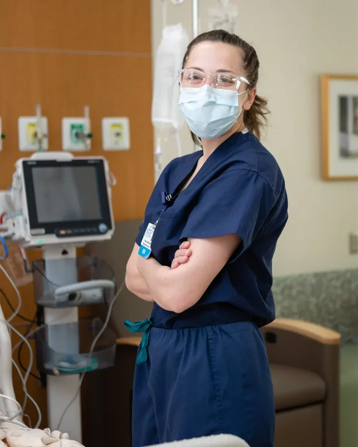 Nurse standing with mask, looking at camera and smiling