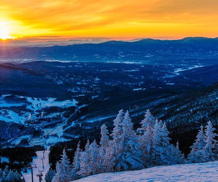 View of the sunset or sunrise on top of a snowy ski mountain