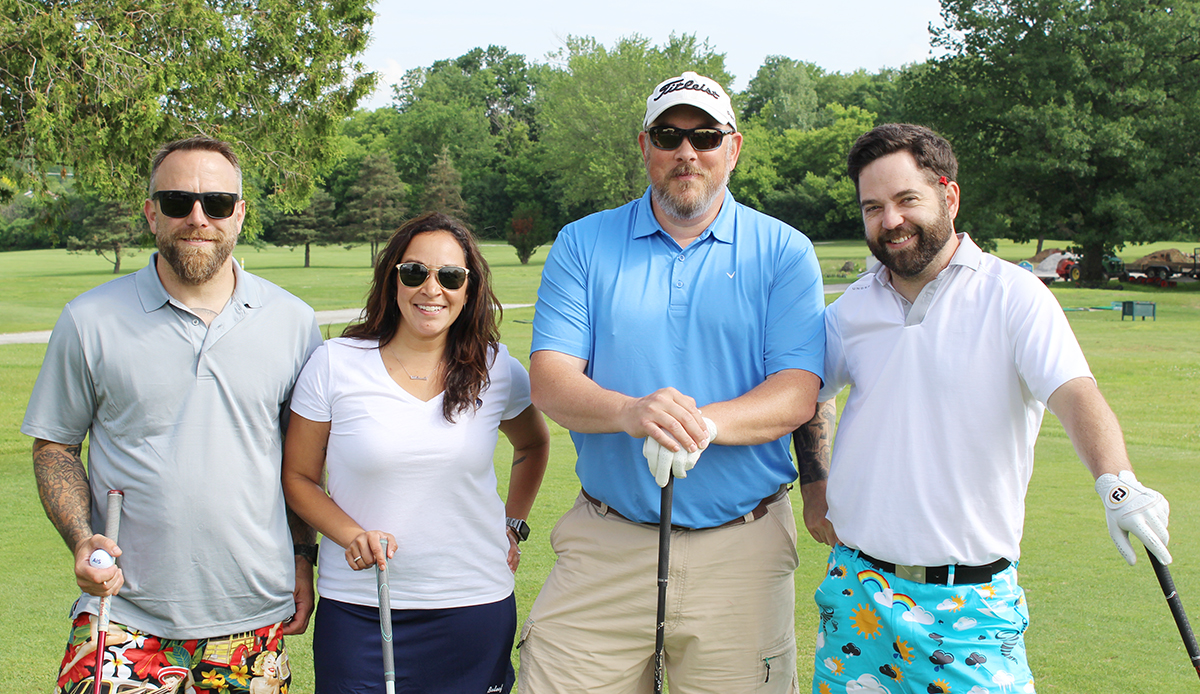 four people smiling on beautiful golf course