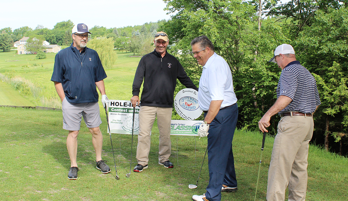 Man putting on green with fellow golfers watching