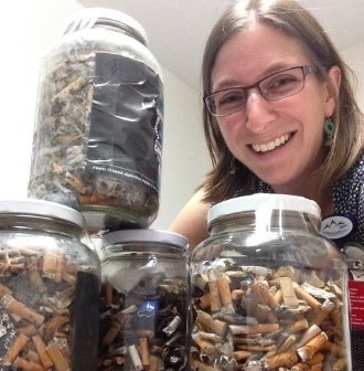 Woman and multiple jars filled with cigarette butts