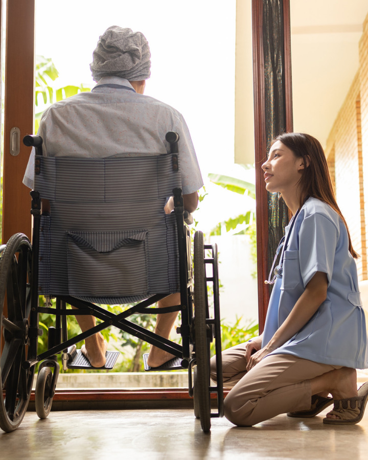 Nurse kneeling beside patient in wheelchair